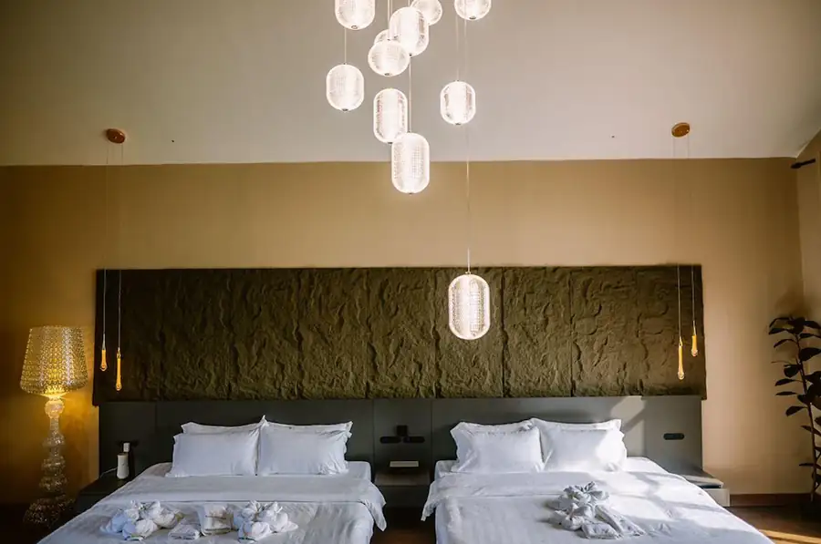 Elegant multi-pendant glass chandelier illuminating two beds inside the Family Room at Turtle Seaweed Resort.